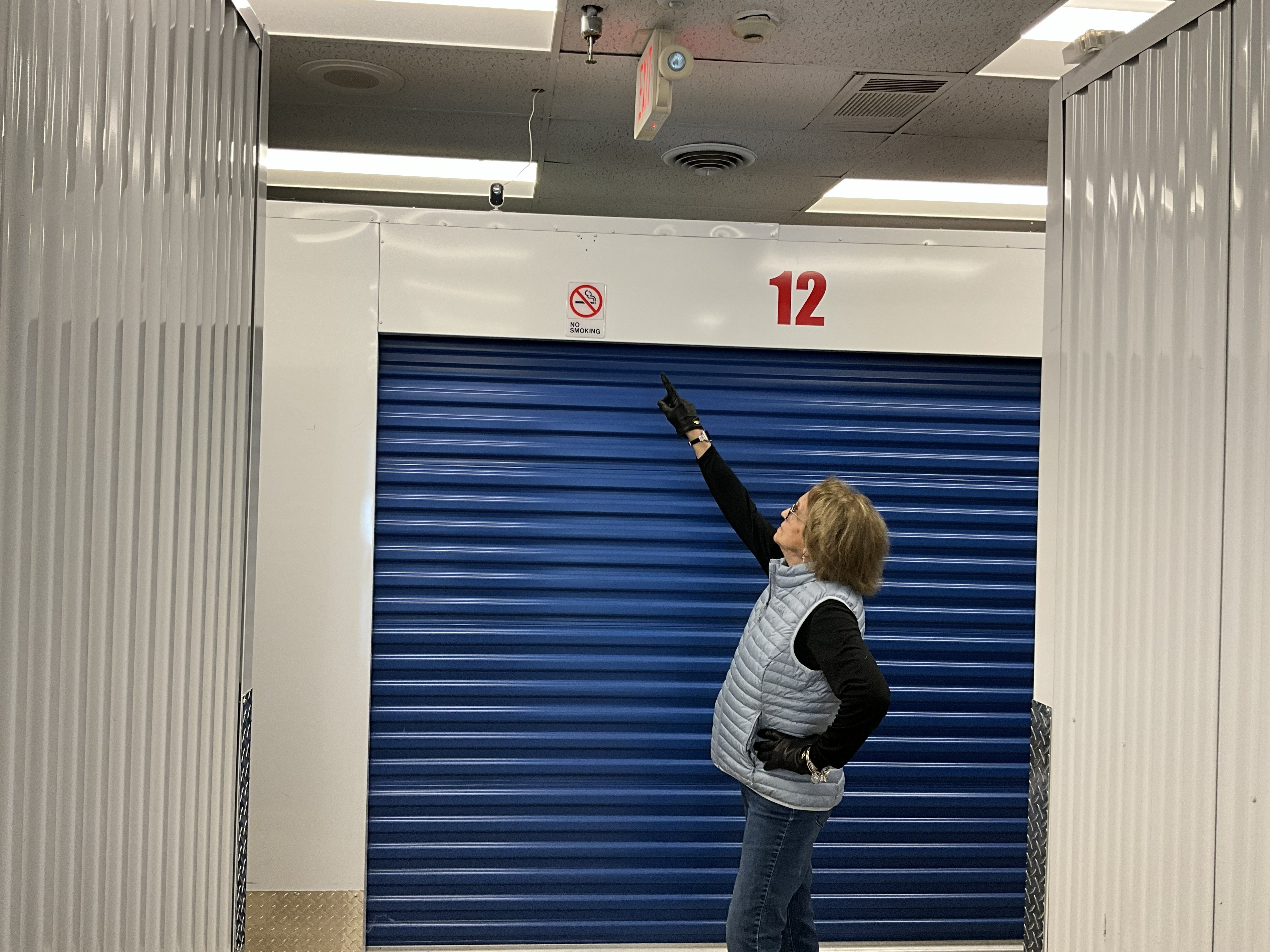 Joanne pointing to an overhead security camera inside the facility