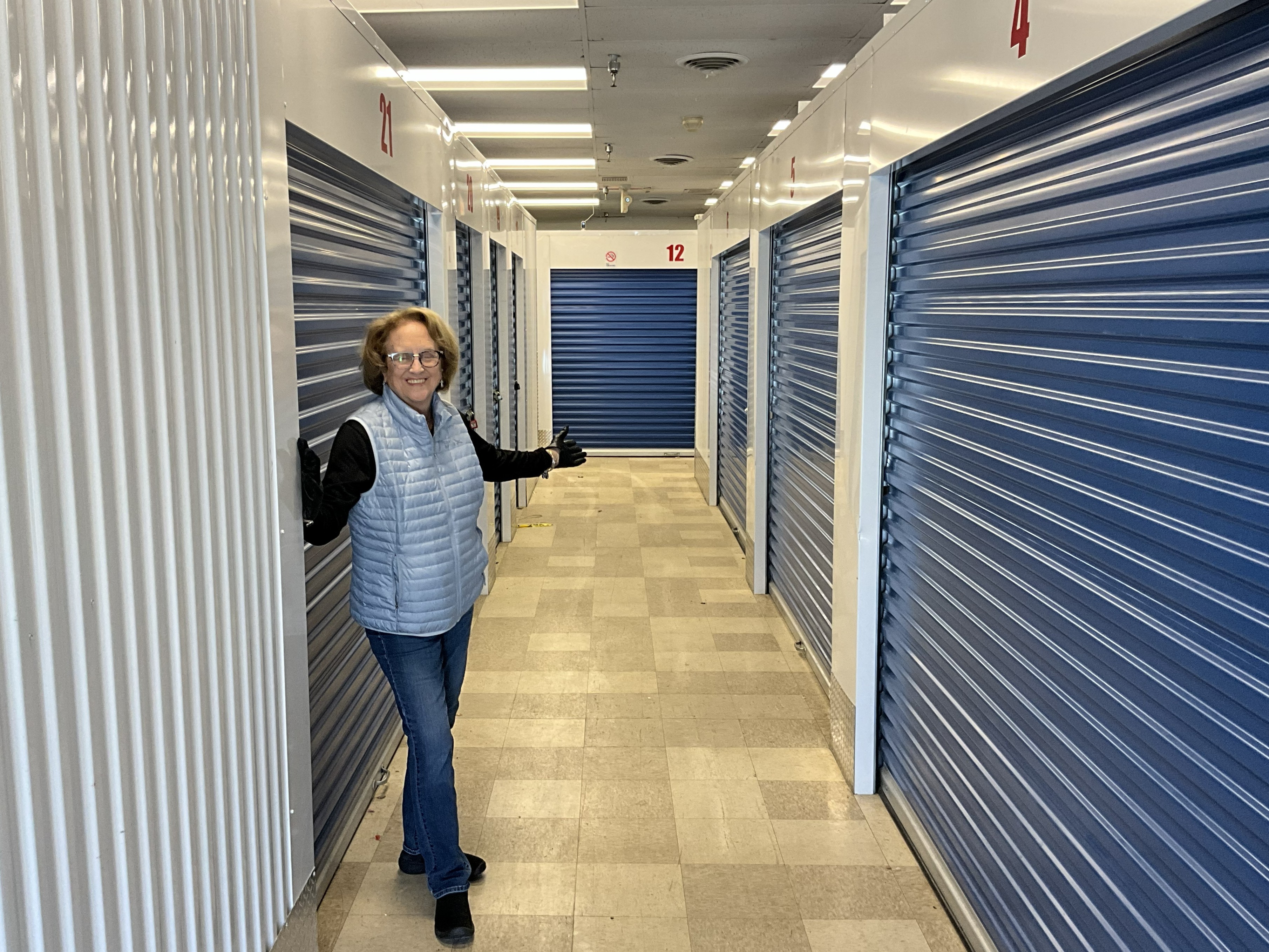 Joanne beside the blue doors in a climate-controlled storage aisle
